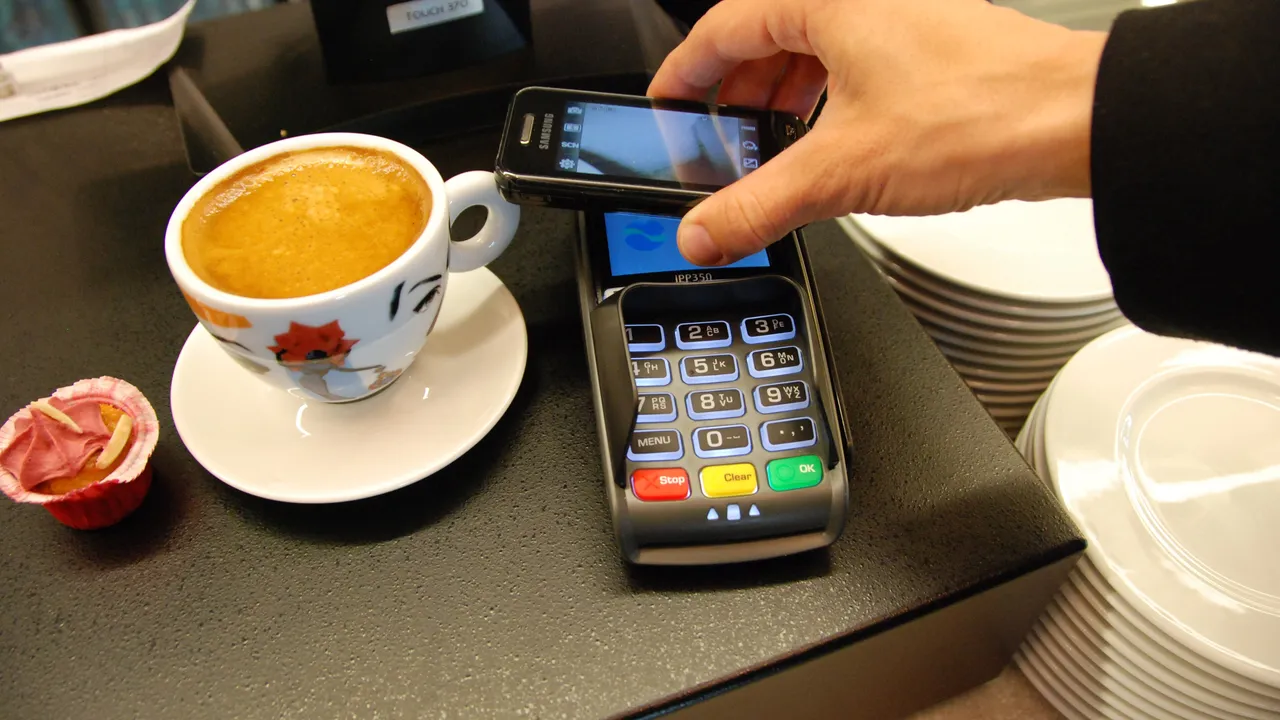 Paiement sans contact avec un smartphone sur un terminal de paiement, sur un comptoir à côté d'un café