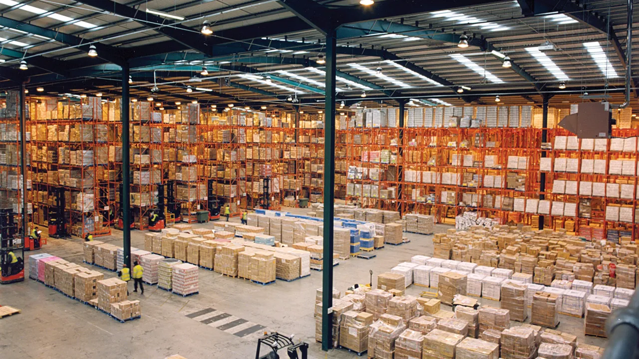 Entrepôt moderne avec rayonnages à palettes, cartons stockés au sol et chariot élévateur