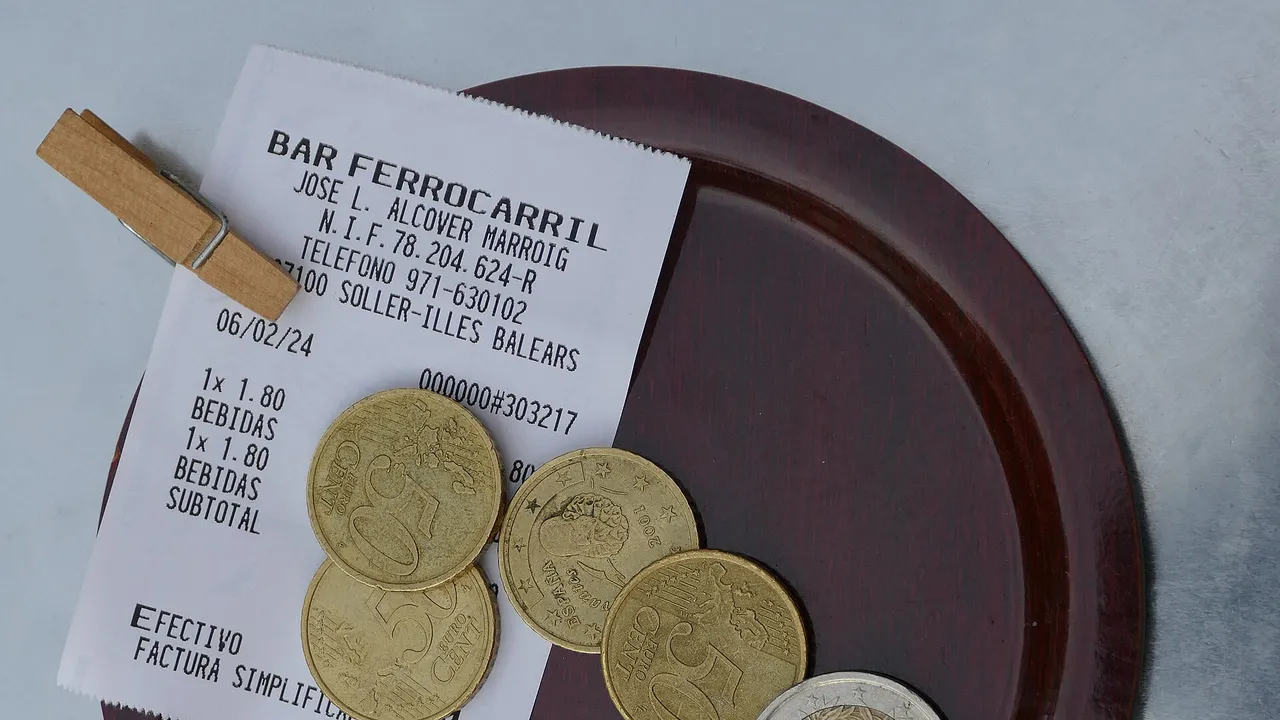 Ticket de caisse réglé et pièces de monnaie posés sur une petite assiette