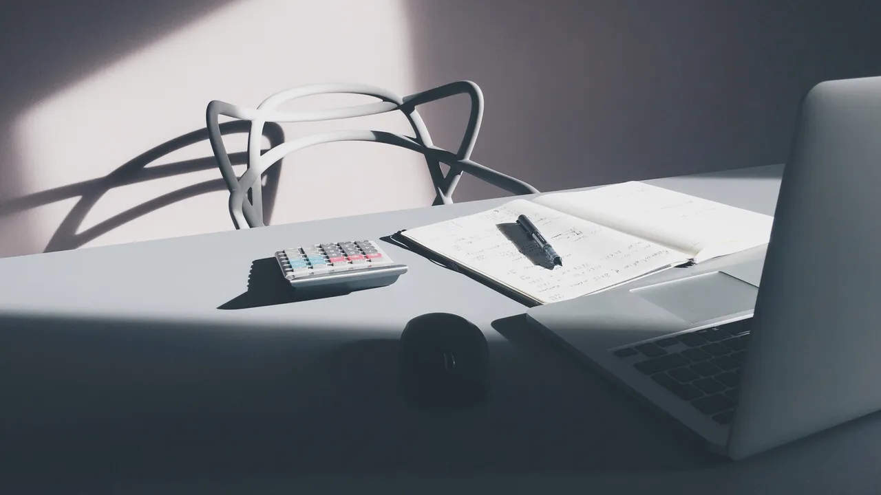 Bureau épuré avec un ordinateur portable, une calculatrice, un carnet et un stylo